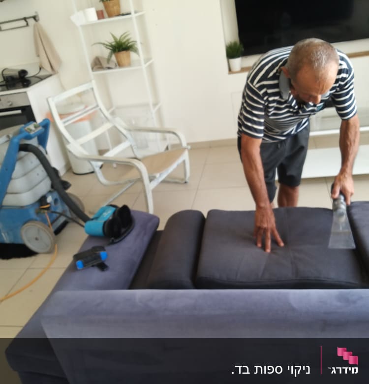 אדם מנקה ספה עם מכונת ניקוי מקצועית